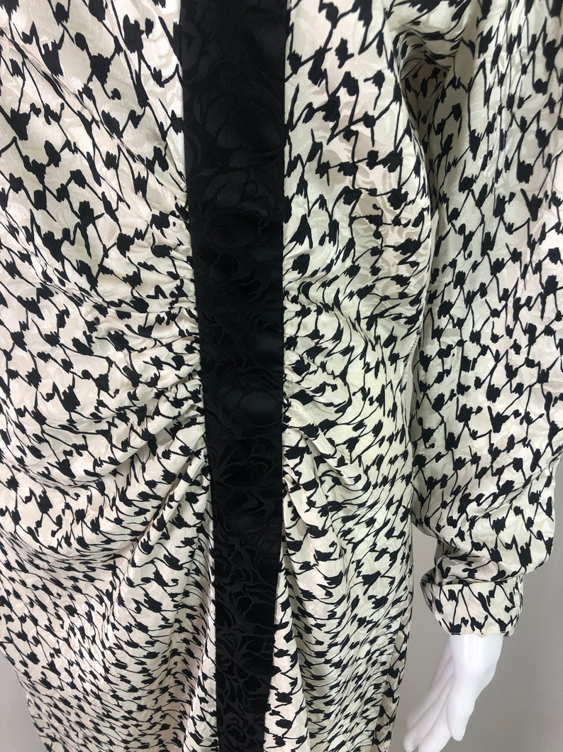 May include: A white and black patterned long-sleeved dress with a black velvet trim down the front.
