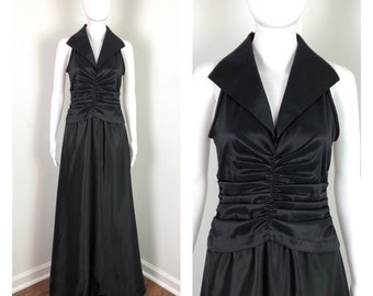 May include: A black sleeveless maxi dress with a large, pointed collar. The dress has a gathered waist and a flowing skirt.