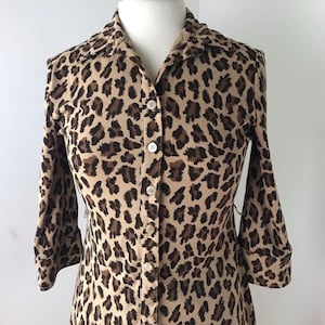 May include: A long-sleeved button-down shirt with a leopard print pattern. The shirt is made of a soft, stretchy fabric and has a relaxed fit.