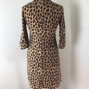 May include: A brown and black leopard print dress with a long sleeve and a fitted silhouette.
