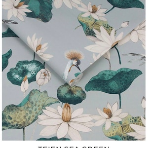 May include: A close-up of a roll of wallpaper with a floral pattern. The design features white lotus flowers, green lily pads, and a bird with a crown on a light blue background. The text "TEIEN SEA GREEN" is at the bottom.