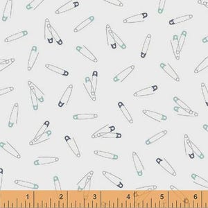 May include: A light gray fabric with a repeating pattern of safety pins. The safety pins are outlined in white with blue and teal accents. The pins are scattered across the fabric in various orientations.