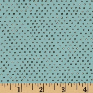 May include: A light blue fabric with a repeating pattern of small, dark brown, slightly irregular squares. The fabric is measured with a wooden ruler marked in inches.