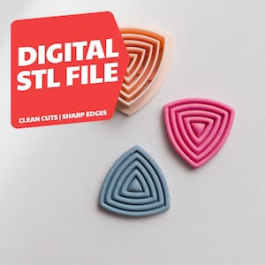 Puede incluir: Tres cortadores de arcilla polimérica en tonos rosa, melocotón y azul, cada uno con forma de triángulo con líneas concéntricas. La imagen incluye el texto "DIGITAL STL FILE" y "CLEAN CUTS | SHARP EDGES".