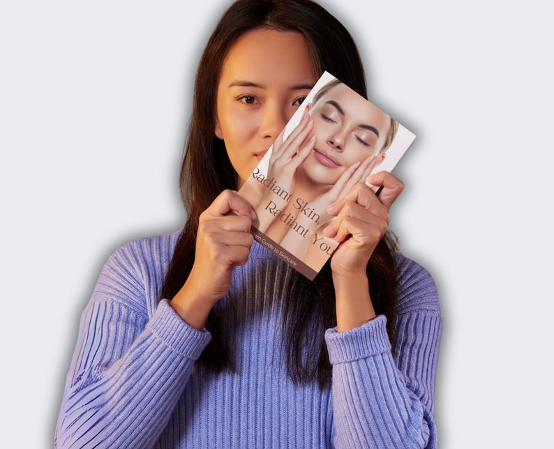 Puede incluir: Una mujer sostiene un libro titulado "Radiant Skin, Radiant You". La portada del libro presenta un primer plano de un rostro con manos tocando las mejillas. La mujer lleva un su&eacute;ter morado claro.