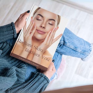 Puede incluir: Una persona sostiene un libro titulado "Radiant Skin, Radiant You: A Modern Guide to Skincare". La portada muestra a una mujer con los ojos cerrados, toc&aacute;ndose la cara. La persona lleva un jersey verde azulado y vaqueros azules.