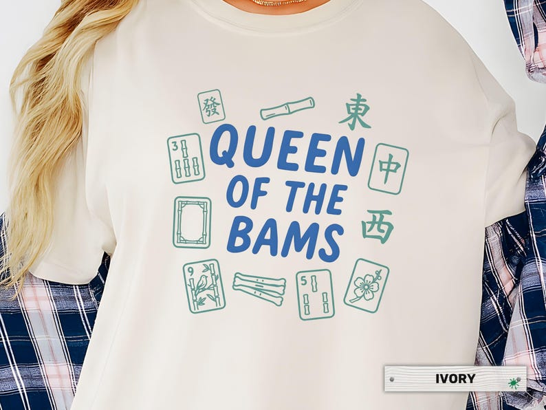 May include: Ivory-colored sweatshirt with the text "QUEEN OF THE BAMS" in blue, surrounded by green Mahjong tiles and Chinese characters. The shirt is a crew neck style.