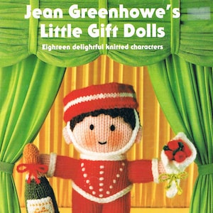May include: A knitted doll dressed as a waiter holding a bottle of champagne and a bouquet of red roses. The doll is standing on a stage with green curtains. The text "Jean Greenhowe's Little Gift Dolls" and "Eighteen delightful knitted characters" is above the doll. The text "Double Knitting Yarn" is below the doll.
