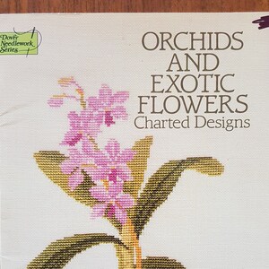 May include: A book cover featuring a cross-stitch design of orchids and exotic flowers. The title reads "Orchids and Exotic Flowers Charted Designs" by Jana Hauschild. The cover has a white background with a Dover Needlework Series logo.