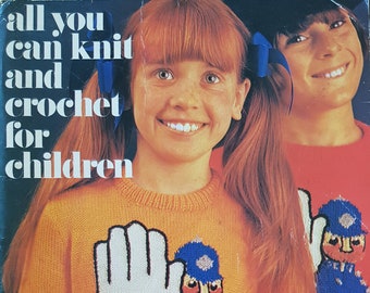 May include: A book cover with the title "all you can knit and crochet for children". The cover features two young girls wearing colorful knitted sweaters with a police officer design. The book is a Golden Hands Special and includes 50 patterns for 50p.