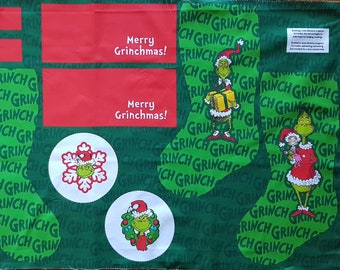 May include: Green fabric with a repeating pattern of the words "Grinch" and "Grinchmas". The fabric features four stocking shapes, two red rectangles, and five circular images. The circular images include a snowflake, a wreath, and a Grinch holding a Christmas ornament. The red rectangles contain the text "Merry Grinchmas!"