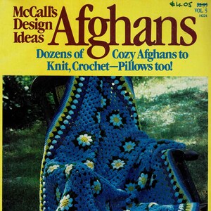 May include: A blue and white crocheted afghan with a daisy pattern is draped over a wicker chair. The afghan has a green and yellow border. The magazine cover reads "McCall's Design Ideas Afghans Dozens of Cozy Afghans to Knit, Crochet-Pillows too!"