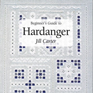 May include: A book titled Beginner's Guide to Hardanger by Jill Carter. The cover features white Hardanger embroidery with intricate cutwork and geometric patterns on a dark blue background. The text Search Press needlecrafts is at the bottom.