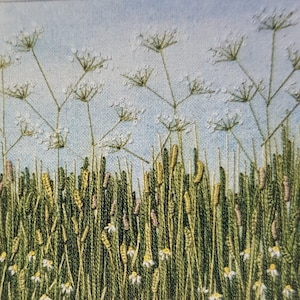 Puede incluir: Obra de arte bordada que representa un campo de flores silvestres. La pieza presenta hierba verde alta, cabezas de semillas amarillas y moradas y flores blancas en forma de margarita. Delicadas flores blancas con finos tallos se extienden hacia un cielo azul claro.