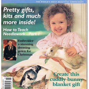 May include: A magazine cover featuring a young girl holding a white and brown bunny rabbit. The magazine is titled "Inspirations: The World's Most Beautiful Embroidery". The cover also features a headline that reads "Pretty gifts, kits and much more inside!" and a sub-headline that reads "How to Teach Needlework... Part I".