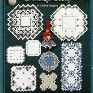 May include: A craft book titled A Taste of Norway In Hardanger Embroidery by Mildred Torgerson, featuring various white Hardanger embroidery patterns, a small doll in a red hat, and a row of Norwegian flag icons on a dark green background.