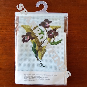 May include: Cross stitch kit featuring a floral design with a yellow background. The kit includes a graph, instructions, 100% cotton fabric, threads, and a needle. Copyright Allura Design Pty Ltd 1984. PO Box 533 Artarmon NSW 2064 Australia. Made in Australia.