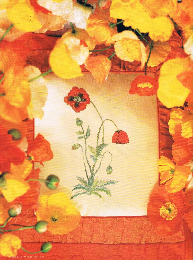 May include: A close-up of a cross-stitch embroidery design featuring a red poppy flower with green leaves and stems. The embroidery is framed by a white border and surrounded by orange and yellow poppy flowers.