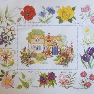 May include: A cross-stitch pattern featuring a cottage surrounded by a variety of flowers, including a poppy, cornflower, rose, sweet pea, daisy, iris, honeysuckle, sweet briar, arum lily, tiger lily, pansy, and dianthus.