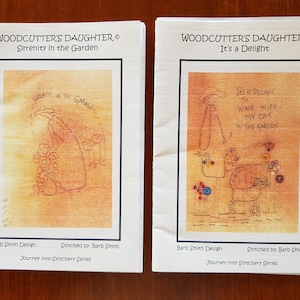 May include: Two embroidery patterns featuring a woman in a garden. The first pattern is titled "Serenity in the Garden" and depicts a woman holding a bouquet of flowers. The second pattern is titled "It's a Delight" and depicts a woman walking with a cat in the garden. Both patterns are part of the "Journey into Stitchery Series" by Barb Smith Design.