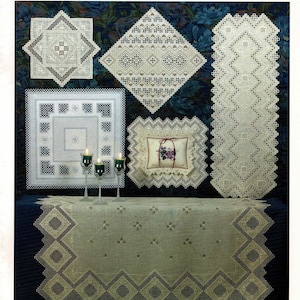 May include: A book cover showcasing a collection of award-winning Hardanger embroidery designs. The cover displays five different embroidery pieces, including a table runner, a pillow, and a tablecloth. The book title is "Award-Winning Designs in Hardanger Embroidery 2001".
