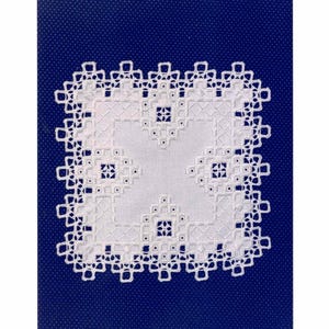 May include: A white square Hardanger embroidery piece featuring intricate satin stitches and a trellis pattern. The text at the top reads: Satin Stitches, Hardangersom by Donna M. Olson, Trellis. The embroidery is displayed against a dark blue background.