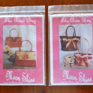 May include: Two pink and white patterned paper bags with the text "The Bead Bag" and "The Bow Bag" on the front. Both bags have the text "Moon Shine... designs by Monica Poole" at the bottom.
