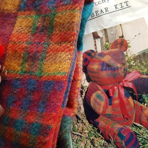 Peut inclure: Un kit d'ours en tissu écossais coloré avec un ours fini, du ruban et d'autres fournitures d'artisanat. L'ours est fait de tissu à carreaux rouge, bleu, jaune et vert. Le kit comprend le texte "BEAR KIT".