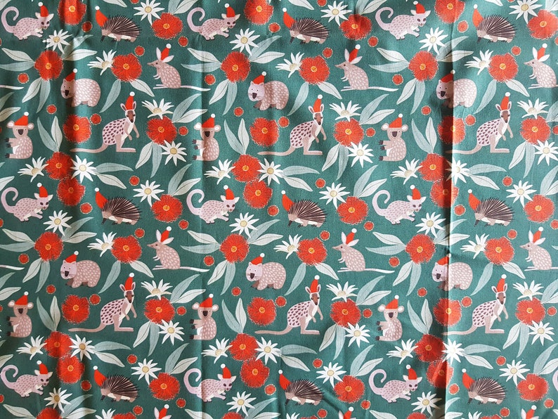 May include: A teal fabric with a repeating pattern of various Australian animals wearing Santa hats. The animals include a koala, a wombat, a kangaroo, a possum, a echidna, and a bandicoot. The fabric also features red gum blossoms and white flowers.