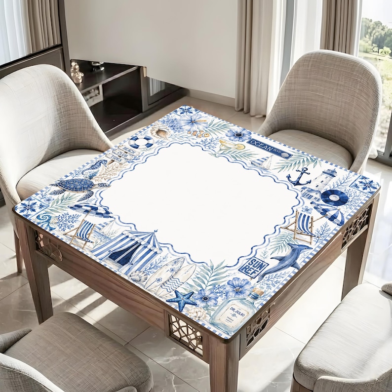 May include: A wooden square table with a decorative beach-themed tablecloth. The tablecloth features a white center framed by a blue border with beach elements like a turtle, dolphin, and surfboard. The table is surrounded by chairs.