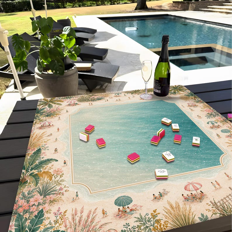 Puede incluir: Un juego de Mahjong con tem&aacute;tica de playa sobre una mesa, con una piscina y asientos al aire libre en el fondo. El tablero del juego presenta una escena de playa con una piscina turquesa, arena y personas. Las fichas de Mahjong rosas, amarillas y blancas est&aacute;n esparcidas por el tablero.