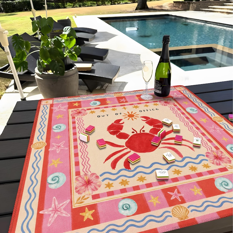 K&ouml;nnte beinhalten: Ein farbenfrohes Spielbrett im Strand-Design mit einer gro&szlig;en roten Krabben-Illustration und dem Text "OUT OF OFFICE". Das Spielbrett hat ein rosa-cremefarbenes Farbschema mit Seesternen, Muscheln und Hibiskusbl&uuml;ten. Mehrere Spielsteine sind darauf verstreut.