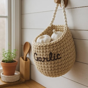 May include: A white ceramic mug with a black handle and the text "But First, Coffee" in a bold, black font. The mug is set against a blurred background, suggesting a cozy setting.