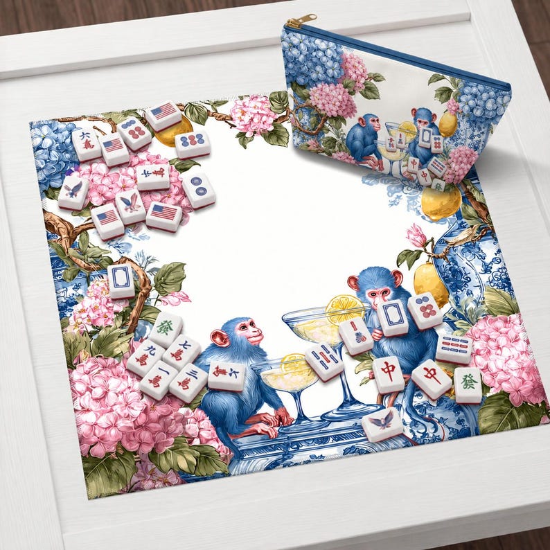 May include: A decorative mat and matching zippered pouch featuring a whimsical design with blue monkeys, cocktails, and Mahjong tiles. The background includes blue and white floral patterns and pink hydrangeas.
