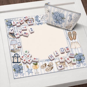 May include: A decorative mahjong set with blue and white striped border, featuring illustrations of seahorses, hydrangeas, and nautical elements. Includes a matching zippered pouch. The mahjong tiles are white with red and blue markings.