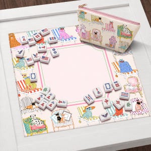 May include: A pink and white mahjong set with dog illustrations, including a matching zippered pouch. The set features tiles with various symbols and American flag designs. The mat has a pink center with a green and pink border.