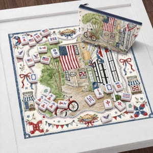 May include: A mahjong set with red, white, and blue tiles, a matching zippered pouch, and a printed mat featuring an Americana scene with flags, shops, and a bicycle. The set is displayed on a white surface.