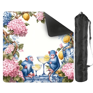 May include: A decorative yoga mat featuring a whimsical design with blue monkeys, cocktails, lemons, and pink hydrangeas. The mat has a black underside and comes with a black carrying bag. The design is set against a white background with blue and white porcelain-style accents.