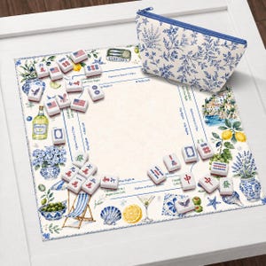 May include: A decorative Mahjong game set with a blue and white floral print cosmetic bag. The game board features a coastal design with lemons, olives, and a beach scene. The Mahjong tiles are white with red and blue markings.