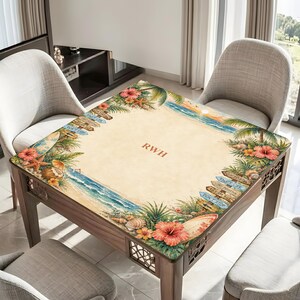 K&ouml;nnte beinhalten: Ein Holztisch mit Strandmotiv. Der Tisch hat einen sandigen Hintergrund mit Meereswellen, Muscheln und tropischen Blumen. Die Initialen "RWH" sind auf dem Tisch aufgedruckt. Dekorative Richtungsschilder und Surfbretter sind ebenfalls enthalten.