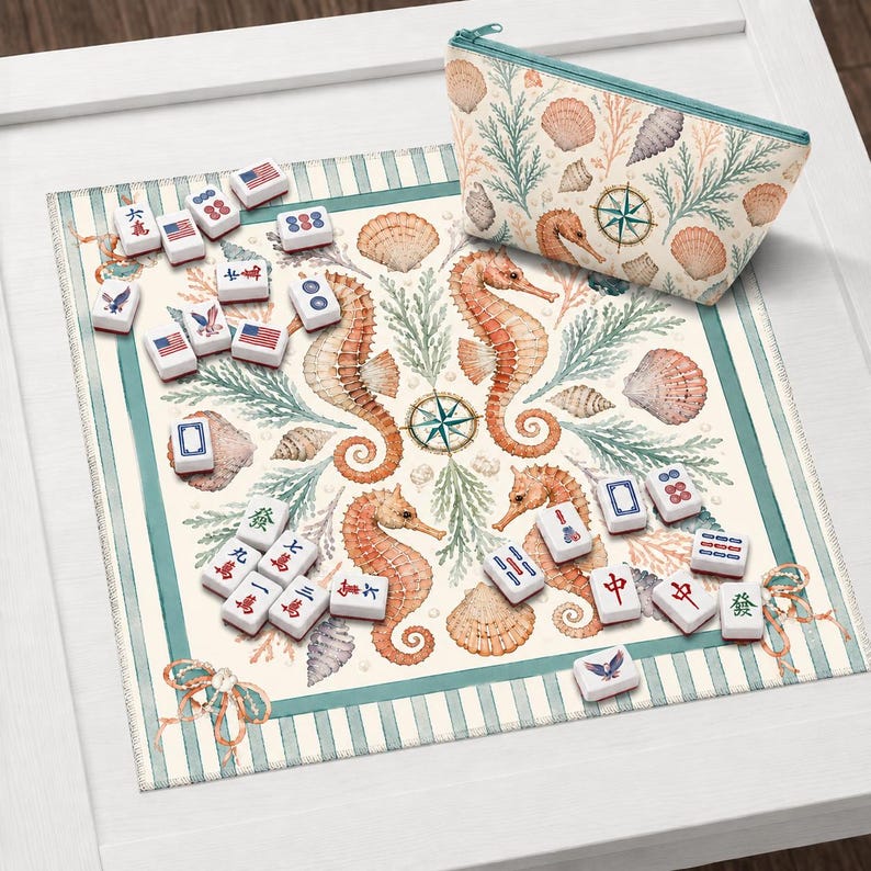 May include: A Mahjong set with a marine theme, featuring seahorses, seashells, and a compass rose design. The set includes tiles with various symbols and a matching zippered pouch. The background is a patterned mat with a striped border.