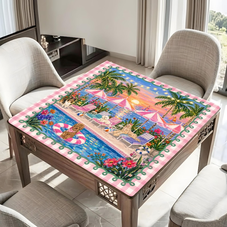 May include: A square table with a decorative beach scene table cover. The cover features a pool, beach chairs, palm trees, and dogs. The border of the table cover is pink and white checkered.