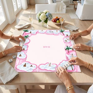 May include: A rectangular mahjong mat featuring a light pink center with the letters RWH in the middle. The border displays a repeating pattern of pink-rimmed swimming pools with blue water, palm trees, and small figures, with mahjong tiles.