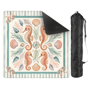 May include: A square beach mat with a nautical design featuring seahorses, seashells, and a compass rose. The mat has a cream background with a striped border in teal and white. A black carrying bag is included.