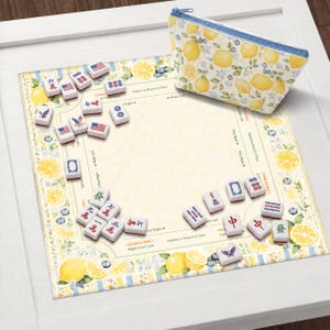 Pu&ograve; includere: Un set di Mahjong con tessere raffiguranti vari simboli e disegni, tra cui bandiere americane. Il set &egrave; disposto su un tappetino decorativo con motivi di limoni e mirtilli. &Egrave; presente anche un astuccio con cerniera abbinato con un motivo a limoni.