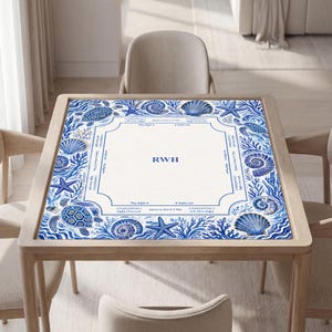 May include: A square mahjong mat featuring a white center with the letters RWH and game instructions, surrounded by a blue and white border decorated with illustrations of sea turtles, starfish, seashells, and coral reef patterns.