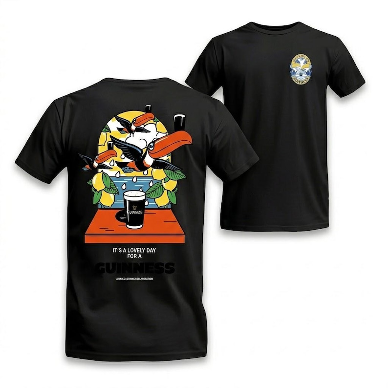 Puede incluir: Camisetas negras con un dise&ntilde;o tem&aacute;tico de Guinness. La parte delantera de la camiseta presenta un peque&ntilde;o emblema, mientras que la parte trasera muestra una colorida ilustraci&oacute;n de tucanes, limones y una pinta de Guinness, con el texto "It's a lovely day for a Guinness."
