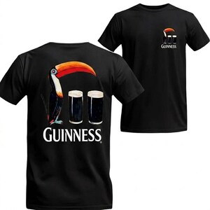 May include: Black t-shirts featuring a toucan with a large orange and red beak, and two pints of dark beer. The word "GUINNESS" is printed below the image on the back of the shirt. A smaller version of the design is on the front.