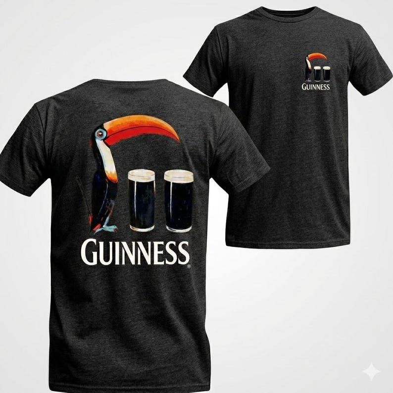 May include: Dark gray t-shirts featuring a toucan with a large orange beak and two pints of stout. The word "Guinness" is printed below the toucan on the back of the shirt. A smaller version of the design is on the front.