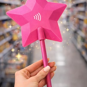 May include: A bright pink star-shaped device with a handle, featuring a white wireless symbol. The star has a faceted design. The device is held in front of a blurred background, with sparkling star accents.
